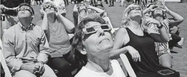  ?? [PHOTO BY DOUG HOKE, THE OKLAHOMAN] ?? Sueann Burton and others behind her watch Monday’s eclipse during the great American solar eclipse party at the Myriad Botanical Gardens in downtown Oklahoma City.