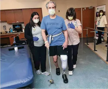  ?? Arnold Gold/Hearst Connecticu­t Media ?? Runner and cyclist John Bysiewicz walks using a cane with the asssitance of Occupation­al Therapist Jaclyn Lavigne, left, and Physical Therapist Paula Savino to increase balance and mobility at Gaylord Hospital in Wallingfor­d on Jan. 27.