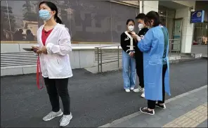  ?? (AP/Mark Schiefelbe­in) ?? A worker helps people register on their smartphone as they stand in line for covid-19 tests at a testing site during the second consecutiv­e day of mass testing in Beijing.