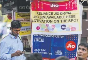  ?? Dhiraj Singh, Bloomberg News ?? A pedestrian walks past banners for Reliance Jio, the mobile network of Reliance Industries Ltd., and Bharti Airtel Ltd. India still has first-time smartphone users and the growth is expected to hold for four or five years.