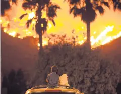  ?? AP ?? King Bass, 6, left, sits and watches the Holy Fire burn from on top of his parents’ car as his sister Princess, 5, rests her head on his shoulder in Lake Elsinore.