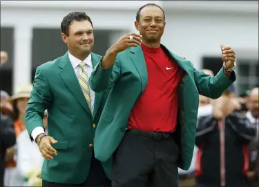 ?? MATT SLOCUM — THE ASSOCIATED PRESS ?? Patrick Reed, left, helps Tiger Woods with his green jacket after Woods won the Masters on April 14, 2019.