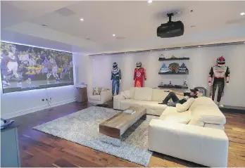  ?? JOHN KENNEY ?? Race car driver Alex Tagliani watches television in his home north of Montreal. Tagliani’s house, which cost roughly $1.4 million, was custom built with smart technology as a central focus.