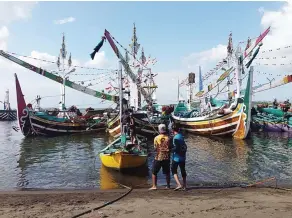  ?? KRIDA HERBAYU/JAWA POS RADAR GENTENG ?? PERSIAPAN: Sejumlah nelayan memeriksa kapal sebelum melaut di Pantai Grajagan, Purwoharjo, kemarin. Meski kawasan mereka masuk wilayah rawan tsunami, mereka tetap tenang dan beraktivit­as seperti biasa.