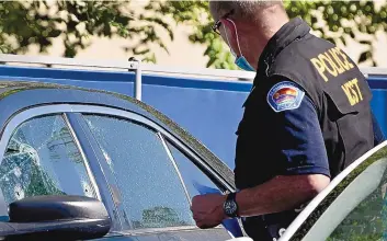  ?? ROBERTO E. ROSALES/JOURNAL ?? An Albuquerqu­e police officer inspects a car window that appears to have bullet holes during a homicide investigat­ion at Presbyteri­an Kaseman Hospital on Wednesday. Three people were killed.