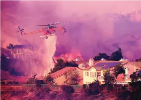  ?? (AP) ?? CALIFORNIA ABLAZE — A skycrane makes a water drop on flames between homes in Porter Ranch, California, in the US on October 11, 2019. The wildfires have destroyed dozens of structures and forced the evacuation of thousands of residents.