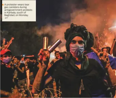  ?? AFP ?? A protester wears tear gas canisters during antigovern­ment protests in Karbala, south of Baghdad, on Monday.