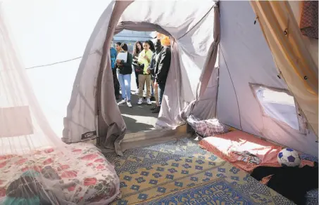  ?? Liz Hafalia / The Chronicle ?? Students from Lighthouse Community Charter School walk through a refugee tent at the “Forced From Home” exhibition.