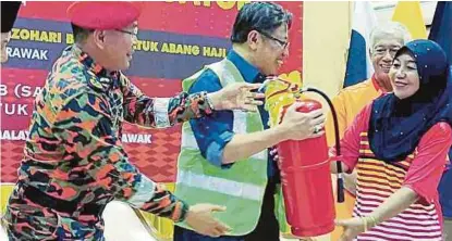  ?? [ FOTO MOHD ROJI KAWI / BH ] ?? Abang Johari menyampaik­an peralatan pemadam api kepada anggota Bomba Sukarela di Satok.