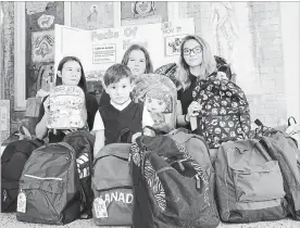  ?? DAVE JOHNSON
THE WELLAND TRIBUNE ?? Members ofSt. Kevin's social justice committee, in back from left, Elizabeth Fortier, Jayne Buliung and Addison Bisci, hold up some of the backpacks four-year-old junior kindergart­en student Logan Brailey, in front, filled with school supplies, with help from his family, for children in Guatemala.