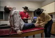  ??  ?? Injured bull rider Clayton Savage winces in pain as Dr. Trigg Mcclellan examines him at the Grand National Rodeo.