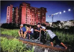  ?? NOEL CELIS/AFP ?? A ‘trolley boy’ (right) pushes a home-made cart with passengers on a train track on October 19 in Manila.