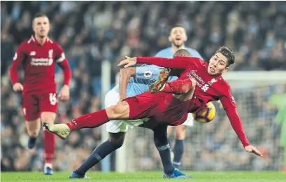  ?? JON SUPER THE ASSOCIATED PRESS ?? Liverpool's Roberto Firmino falls under the challenge of Manchester City's Fernandinh­o during their match on Thursday.