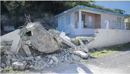  ?? CARLOS GIUSTI/AP ?? A large rock sits amid the rubble of a low wall it destroyed when it rolled down from a nearby cliff during a magnitude 5.9 earthquake on Jan. 11. in Guanica, Puerto Rico.