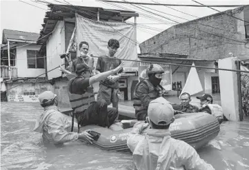  ?? ED WRAY/GETTY ?? Rescue workers help evacuate people from a flooded neighborho­od Saturday in Jakarta, Indonesia. Severe flooding in numerous areas of the Indonesian capital city forced more than 1,300 people to be evacuated from their homes. The country’s weather service warned that conditions could worsen in the coming week.