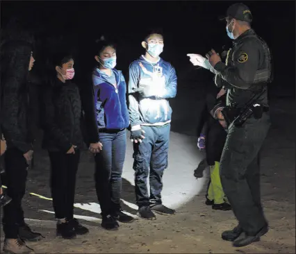  ?? The Associated Press file ?? Migrants from Guatemala and Honduras are questioned by a Border Patrol agent after being smuggled on an inflatable raft in Roma, Texas.