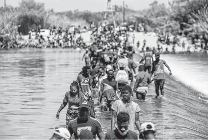  ?? Jordan Vonderhaar / Getty Images ?? Migrants cross the Rio Grande near a camp under the internatio­nal bridge between Del Rio and Ciudad Acuña, Mexico. Since Friday, 3,300 migrants have been removed from the camp to planes or detention centers, Border Patrol Chief Raul Ortiz said.