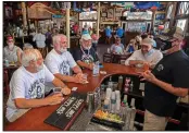  ?? (AP/Florida Keys News Bureau/Rob O’Neal) ?? Charlie Boice (center, in dark shirt) and fellow Hemingway lookalikes Dusty Rhodes (from left) and Tim Stockwell chat with bartender Lou Gammel at Thursday’s reopening of Sloppy Joe’s in Key West, Fla.