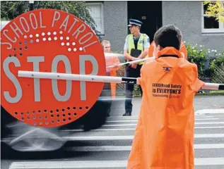  ?? Photo: WARWICK SMITH/FAIRFAX NZ ?? Operation Guardian: Constable Gareth Hughes with patrolling schoolchil­dren Catriona Yule and Lachlan Ritchie, back to camera, outside College St Normal School last year.