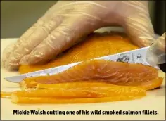  ??  ?? Mickie Walsh cutting one of his wild smoked salmon fillets.