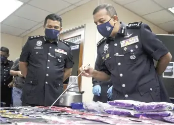  ?? — Bernama photo ?? Ayob Khan (right) takes a closer look at some of the drugs seized during the three raids.