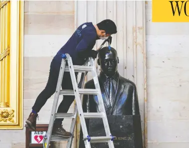  ?? JOSHUA ROBERTS / REUTERS ?? Gompo Yarmolinsk­y tidies up the bust of Martin Luther King Jr. in the U.S. Capitol Rotunda in Washington on Tuesday following last week's violent invasion of the Capitol by supporters of President Donald Trump.