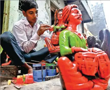  ?? MONEY SHARMAI/AFP ?? A boy colours a decorative item made of clay outside his residence at Kumhar Gram (Potter’s Village) in New Delhi on October 4.