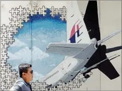  ?? MANAN VATSYAYANA/AFP ?? A man walks in front of a mural of missing Malaysia Airlines MH370 plane in an alley in Shah Alam, Malaysia.