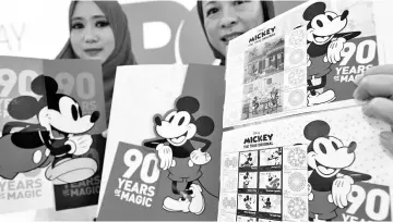  ?? - Bernama photo ?? Pos Malaysia Head of the Stamp and Philately Unit Diyana Lean Abdullah (right) and a staff Noraini Mohd Salleh with the Mickey Mouse stamp series in conjunctio­n with the famous Disney animated character’s 90th birthday.