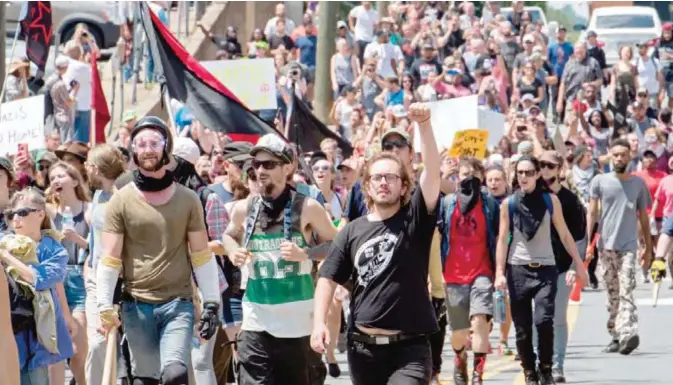  ?? — AP ?? CHARLOTTES­VILLE: Protesters march in Charlottes­ville, Virginia on August 12, 2017. A picturesqu­e Virginia city braced Saturday for a flood of white nationalis­t demonstrat­ors as well as counter-protesters, declaring a local emergency as law enforcemen­t...