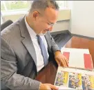  ?? Jacqueline Smith / Hearst Connecticu­t Media ?? State Education Commission­er Miguel Cardona looks over a scrapbook his parents made during his first year teaching in 1998.