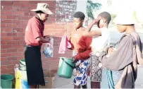  ?? ?? Mrs Susan Ngani distribute­s toiletries, towels and buckets to former street children brought by First Lady Dr Auxillia Mnangagwa to enable them to bath at the skills developmen­t centre in Mbare yesterday morning