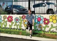  ??  ?? Tim Gibson, creator of the Ten Thousand Flowers mural, stands in front of the mural behind borough hall.