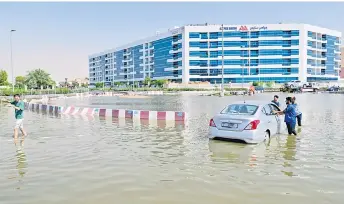  ?? ?? People recover a stranded car on a flooded street in Dubai following heavy rains.