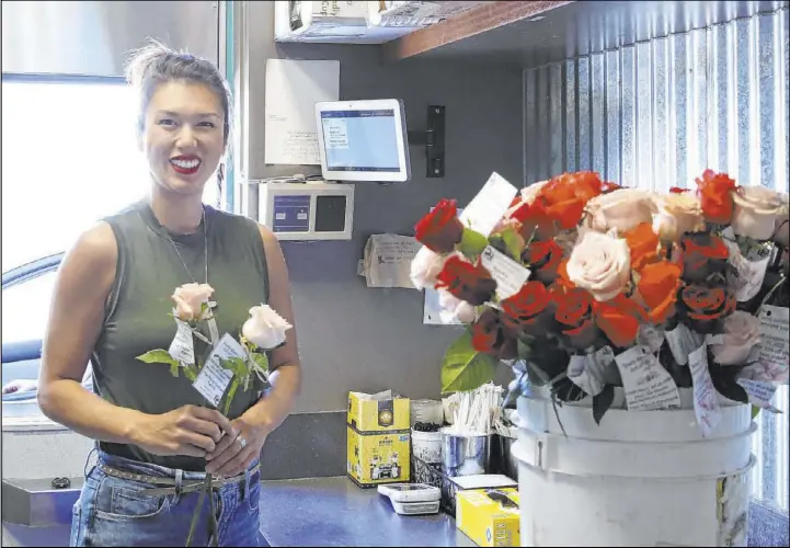  ?? Bizuayehu Tesfaye Las Vegas Review-Journal @bizutesfay­e ?? Juanny Romero, owner of Sunrise Coffee, hands out long-stem roses to drive-thru customers on April 1. A florist gave Romero the roses in exchange for coffee.