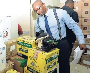  ?? NORMAN GRINDLEY/CHIEF PHOTO EDITOR ?? ACP Clifford Chambers points to fake Wray & Nephew rum among other counterfei­t goods seized by the police.