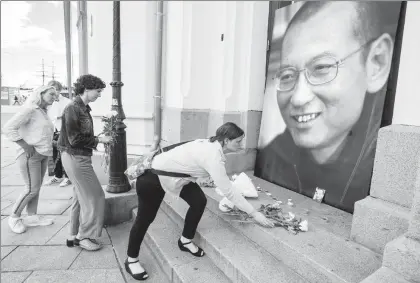  ??  ?? La gente pone flores y velas frente a una foto de Liu Xiaobo, colocado en las calles de Oslo. Autoridade­s informaron de la muerte del preso político más prominente de China ■ Foto Ap