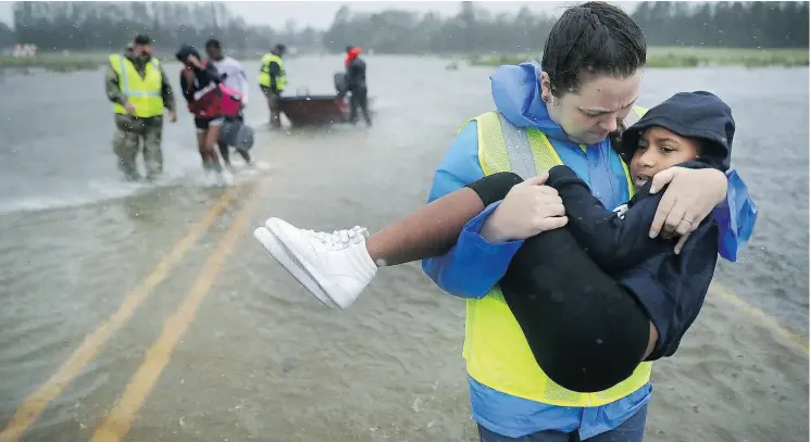  ?? CHIP SOMODEVILL­A / GETTY IMAGES ?? Volunteer Amber Hersel helps rescue seven-year-old Keiyana Cromartie and her family from their flooded home in James City, North Carolina.