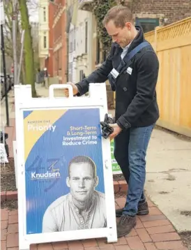  ?? KEVIN TANAKA/FOR THE SUN-TIMES ?? 43rd Ward Ald. Timmy Knudsen sets up a sign outside the Old Town Triangle Associatio­n on Tuesday.