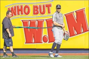  ?? Kathy Willens / Associated Press ?? Yankees OF/DH Giancarlo Stanton, right, who has been out the much of the season with various injuries, takes a break as he works with a trainer and a resistance band in the outfield on Wednesday in New York.