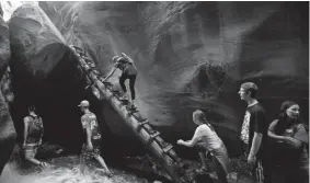  ?? Steve Griffin, The Salt Lake Tribune ?? Hikers climb a ladder made from a tree at the first falls of the Kanarravil­le Falls hike in Kanarravil­le, Utah, in 2016.