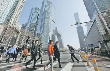  ??  ?? People cross a street in the Central Business District (CBD) one day before the opening session of the National People’s Congress (NPC) in Beijing, China. — Reuters photo