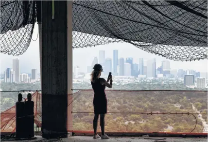  ?? Brett Coomer photos / Houston Chronicle ?? DeeAnn Thigpen takes a photo from the 26th floor, with a view of downtown, at Arabella, a 33-story residentia­l tower under constructi­on just inside the West Loop off San Felipe. Many potential residents also like a view of the Uptown area.