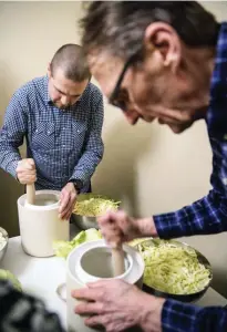  ??  ?? Ungefär hälften av deltagarna i Nordkrauts workshoppa­r med mjölksyrni­ng är män. Olli Saarinen (till vänster) och Harri Lönnblad använder redskap i trä för att blanda in saltet i kålstrimlo­rna och pressa ut vätskan ur massan.