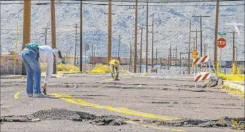  ?? L.E. Baskow Las Vegas Review-Journal @Left_Eye_Images ?? Scientists working alongside the USGS measure and monitor the extensive cracks that have opened up and forced road closures in Trona, Calif.