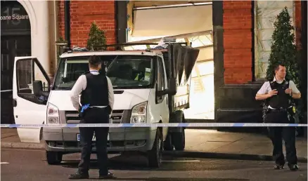  ??  ?? Smash and grab: Police stand guard by the raiders’ van, abandoned outside the destroyed shop front