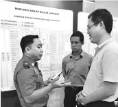  ??  ?? A file photo of Tan (right) talks to a JPAM officer on the process of applying for flood assistance.