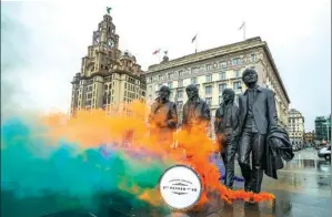  ?? PETER BYRNE / ASSOCIATED PRESS ?? Smoke flares are set off during a photo call by the Beatles' statue on Liverpool's waterfront, in Liverpool, England, on Wednesday.