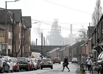  ?? ?? A person walks across the road in a residentia­l neighbourh­ood near to the Tata Steel Port Talbot.