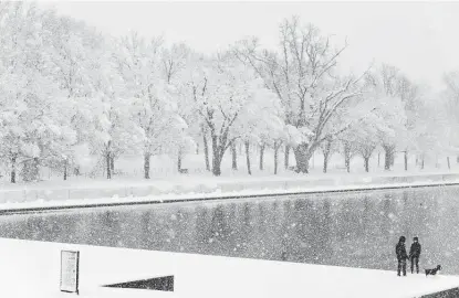  ?? Alex Brandon / Associated Press ?? People walk a dog near the reflecting pool of the Lincoln Memorial in Washington, D.C., on Monday. Heavy snowfall, coupled with closings caused by the surge in coronaviru­s cases, forced much of the city to close.